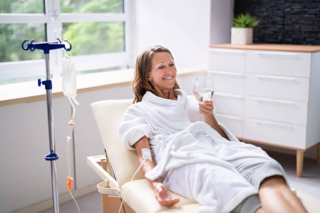 Woman taking IV therapy at a clinic while drinking water