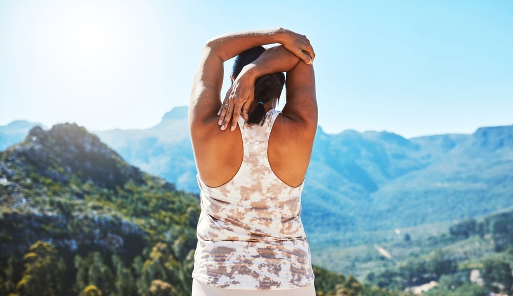 Woman's back, fitness and stretching with mountain view for start of exercise or wellness routine