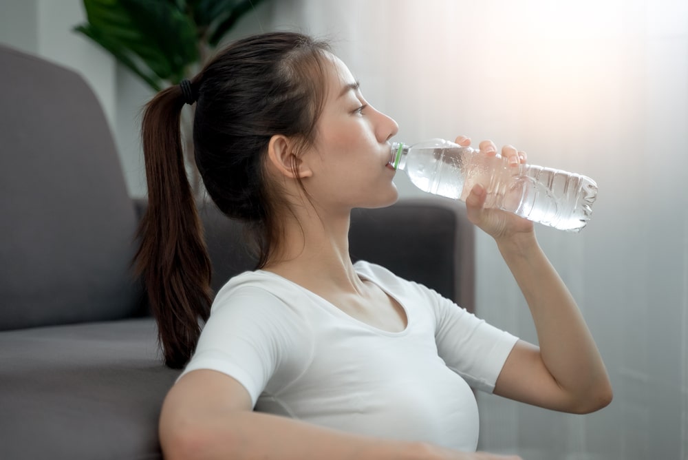 woman drinking water after exercise to replenish dehydration